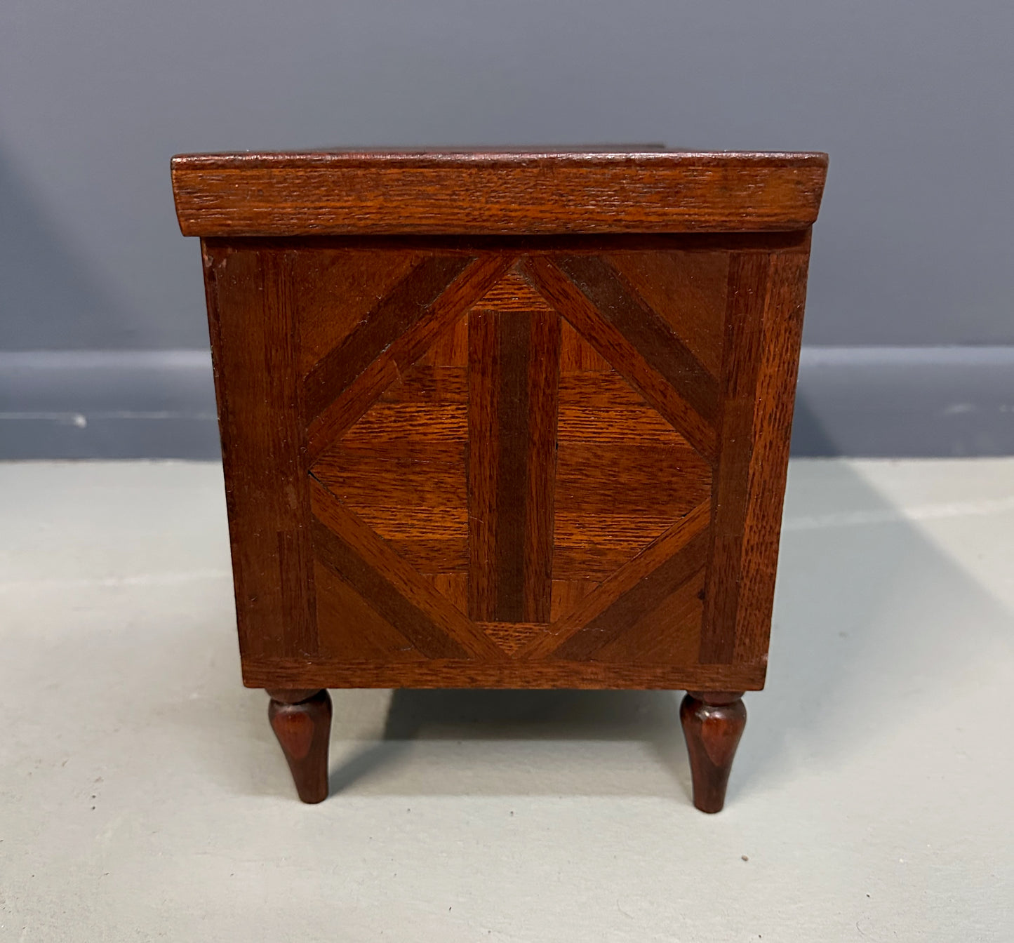 Miniature marquetry blanket chest dated 1910, handcrafted by Flora Boyer of Pennsylvania, featuring intricate geometric inlay patterns in warm-toned wood and a brass keyhole on the front