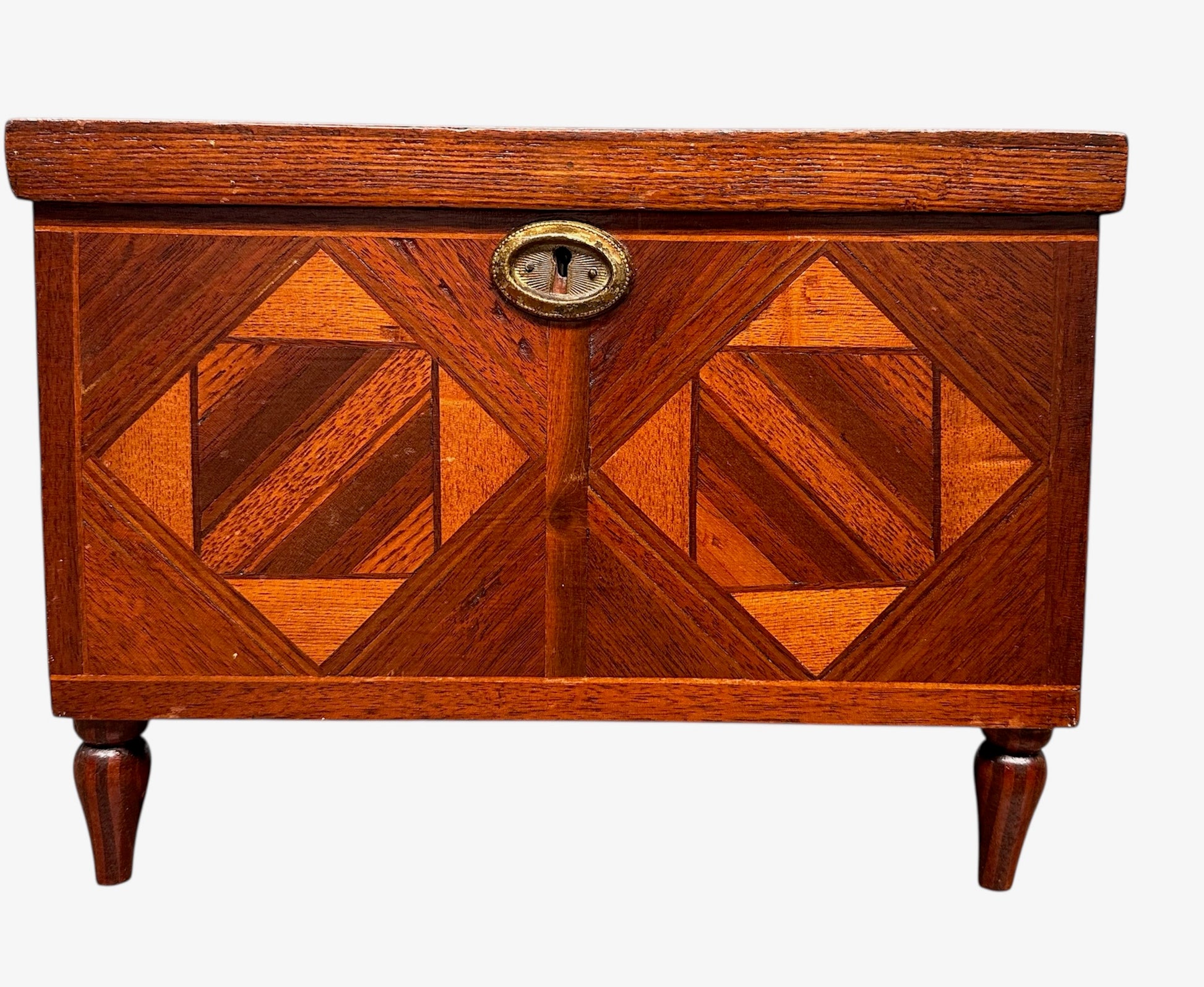 Miniature marquetry blanket chest dated 1910, handcrafted by Flora Boyer of Pennsylvania, featuring intricate geometric inlay patterns in warm-toned wood and a brass keyhole on the front